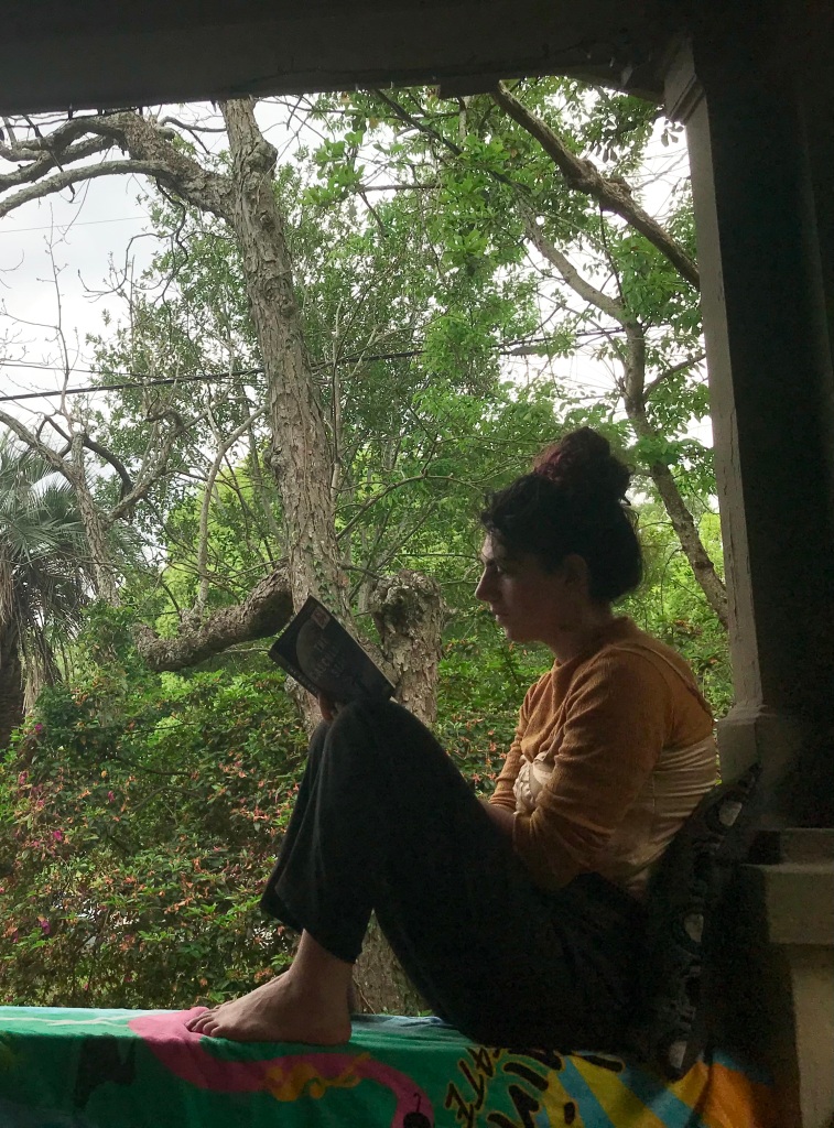 23-year-old Rebecca sits reading on the wide railing of her front porch in Florida, too engrossed in her book to realize she's being photographed.
