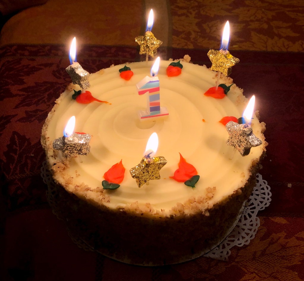 A delicious carrot cake sits on the kitchen table, decorated with burning candles.