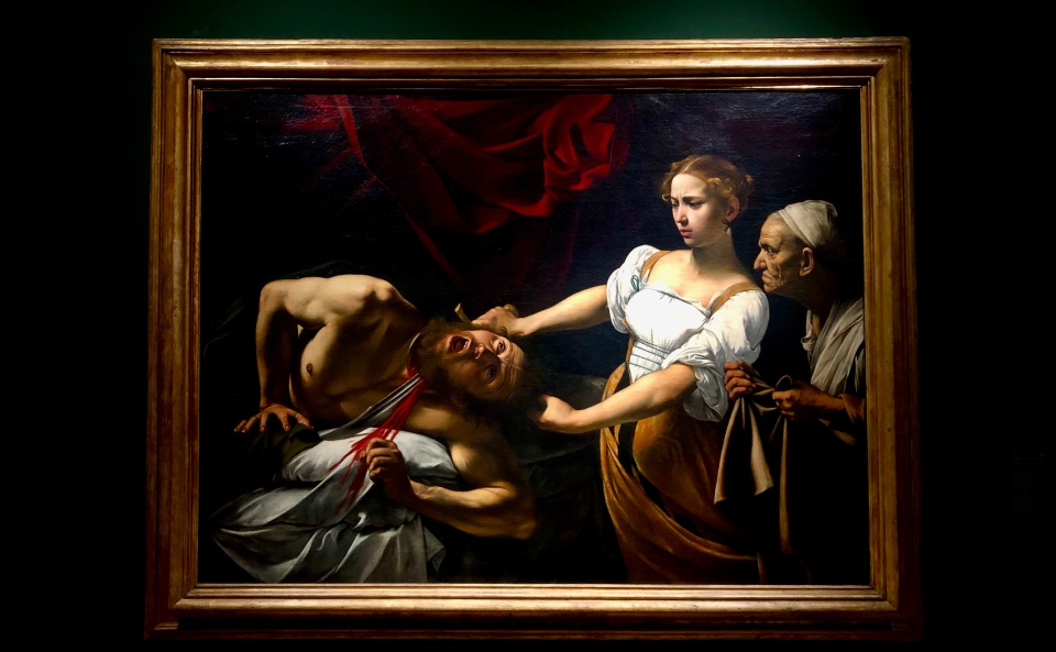 Caravaggio's painting of Judith beheading Holofernes: Judith uses a sword to sever the head of a naked man woken in horror from his sleep, while her elderly handmaid waits patiently to receive the head in her sack.