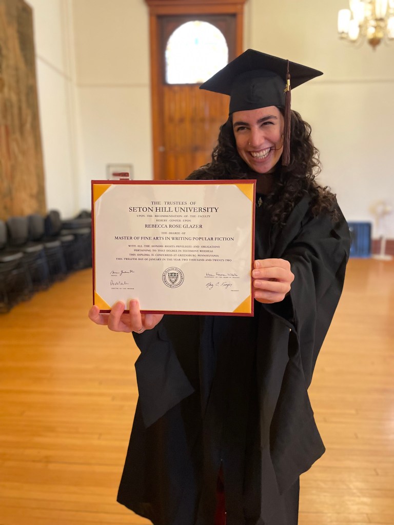 Rebecca holds up her MFA diploma,