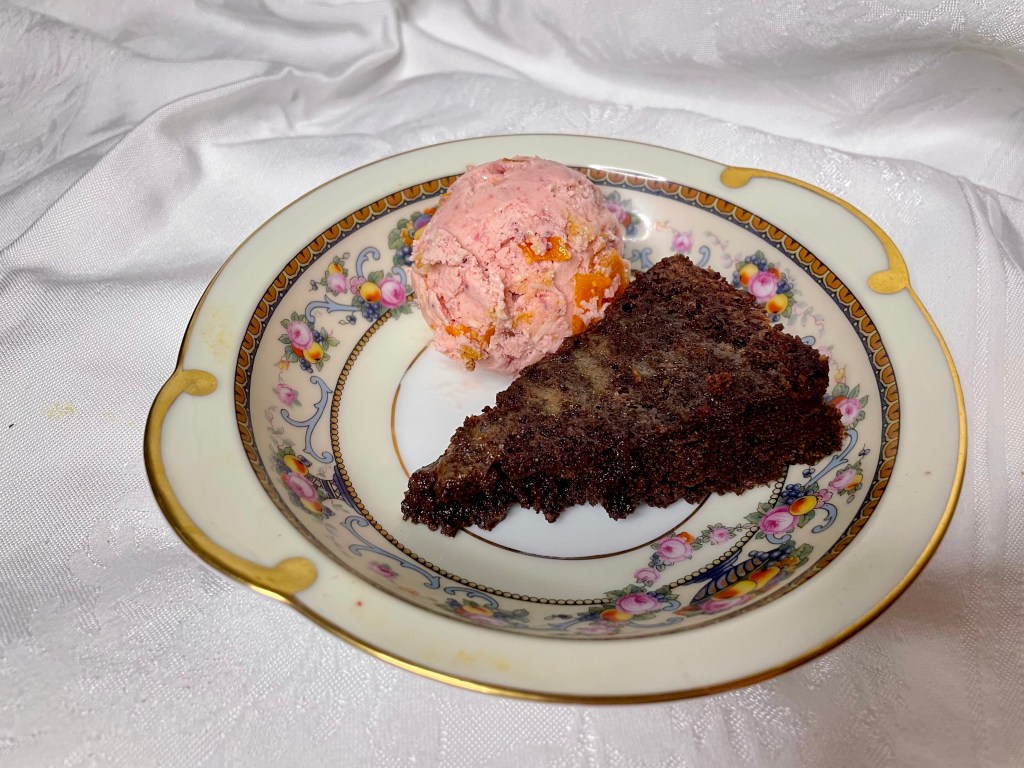 A bowl with flourless chocolate cake and a scoop of bright-pink ice cream.